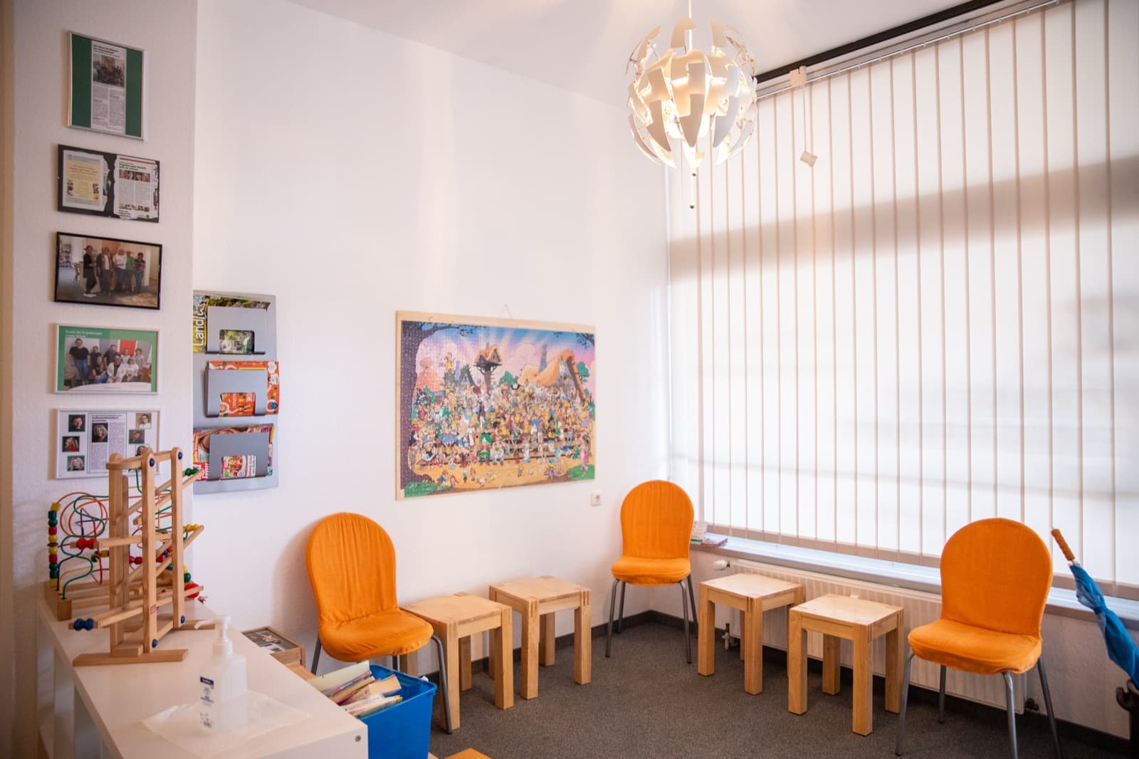 Heller Raum mit großem Fenster und orangen Stühlen für Gruppen und Wartebereich